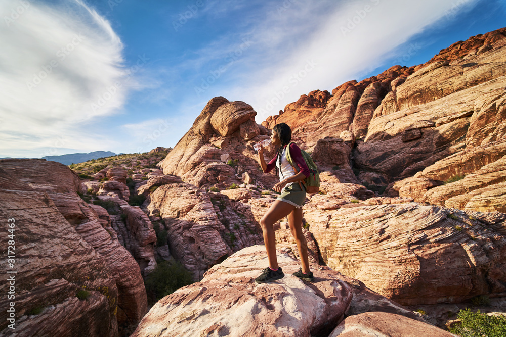 female backpacker drinking from water bottle at red rock canyon inside basin