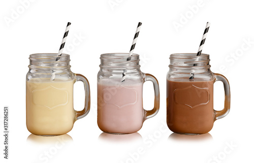 Banana, Strawberry and Chocolate milkshakes in Mason Jar glasses, with paper straws, isolated on a white backdrop