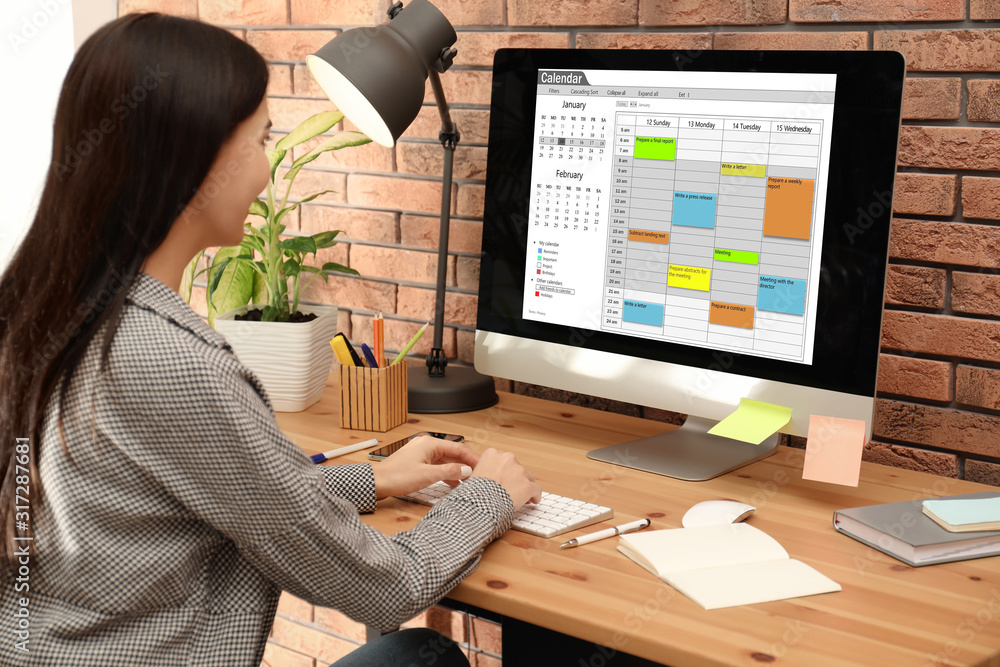 Young woman using calendar app on computer in office