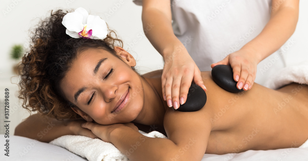 Relaxed woman getting hot stones arm massage in spa