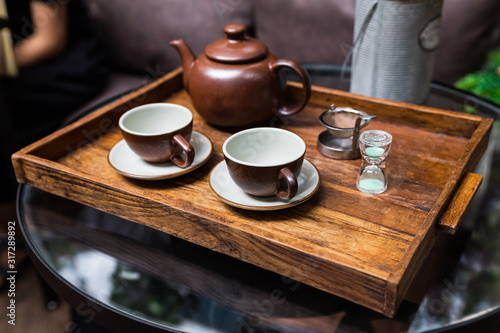 Ceramic vintage cups, mug and small sand clock, equipment for making dry flower with tea stainless steel tea strainer infuser in wooden tray.