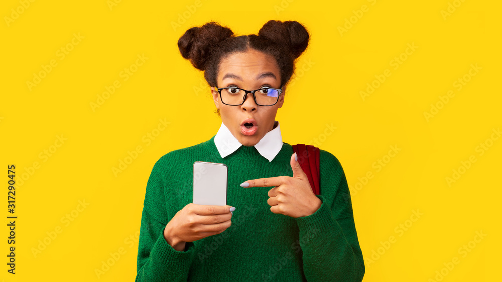 Closeup of amazed black teen pointing at mobile phone Closeup of amazed black teen pointing at mobile phone