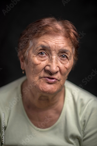 Portrait of an old woman against a dark background. Photographed close-up. © shymar27