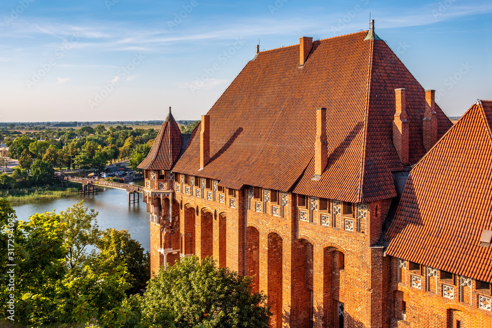 Aerial panoramic view of the monumental gothic Grand Masters’ Palace in the High Castle part of the medieval Teutonic Order Castle by the Nogat river in Malbork, Poland Aerial panoramic view of the monumental gothic Grand Masters’ Palace in the High Castle part of the medieval Teutonic Order Castle by the Nogat river in Malbork, Poland