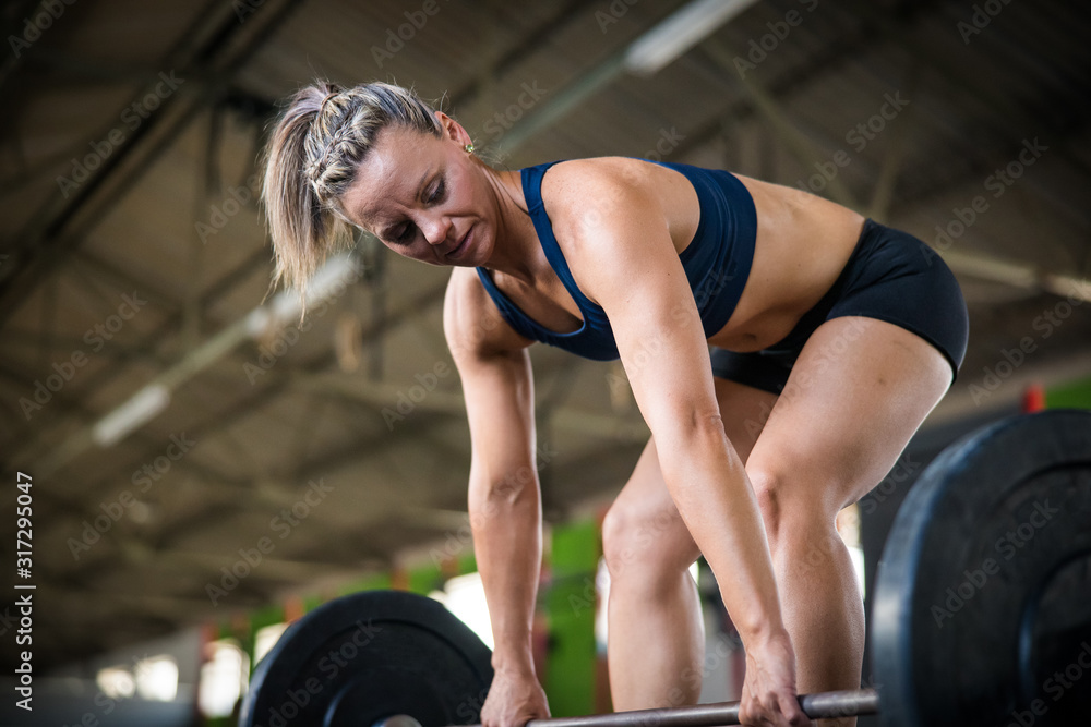 Female fitness model doing cross fit power lifting exercises in a gym Female fitness model doing cross fit power lifting exercises in a gym