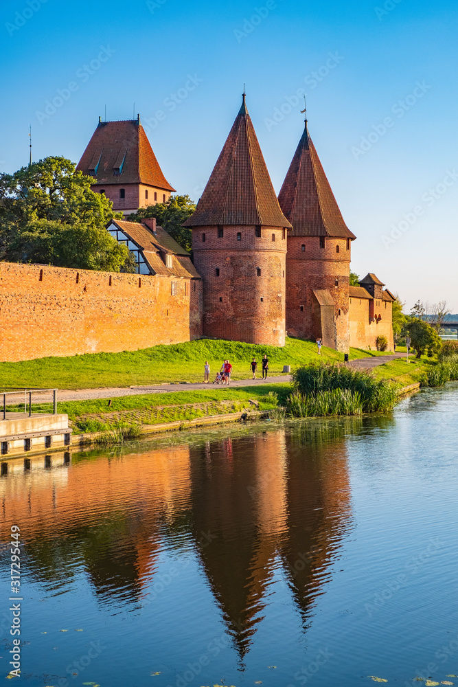 Panoramic view of the western gate with defense towers of the Medieval Teutonic Order Castle in Malbork, Poland at the Nogat river bank