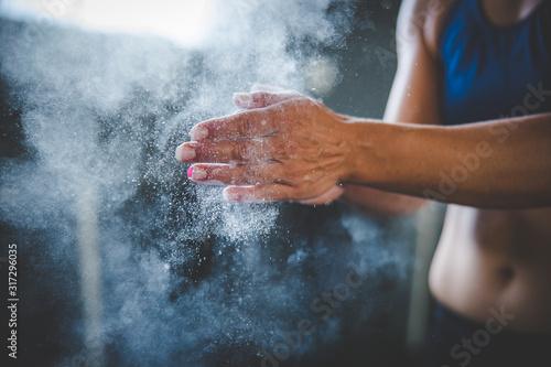 Female fitness model clapping hands with talcum powder in a gym before weight training