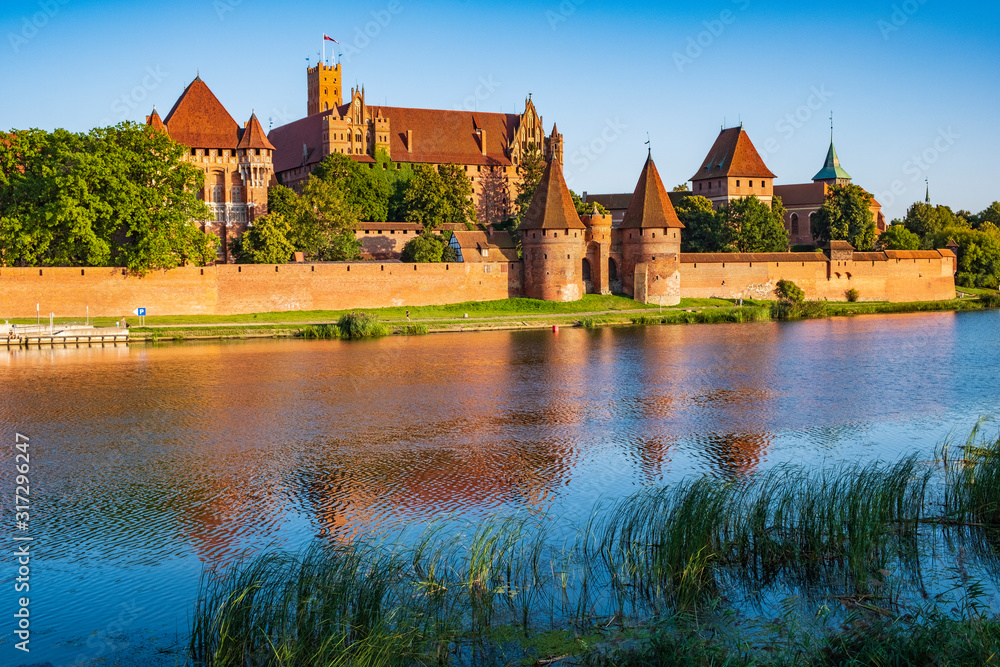 Fototapeta premium Panoramic view of the defense walls and towers of the Medieval Teutonic Order Castle in Malbork, Poland from across the Nogat river