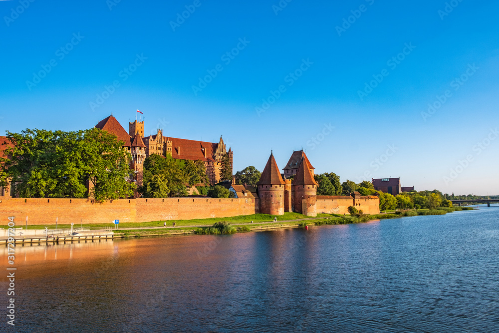 Panoramic view of the defense walls and towers of the Medieval Teutonic Order Castle in Malbork, Poland from across the Nogat river Panoramic view of the defense walls and towers of the Medieval Teutonic Order Castle in Malbork, Poland from across the Nogat river