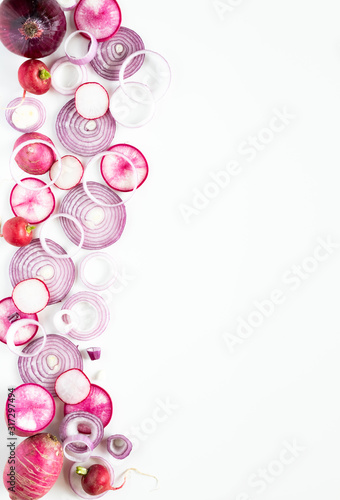A top down vertical view of a border of overlapping slices of red onion, daikon and radishes. © Carey
