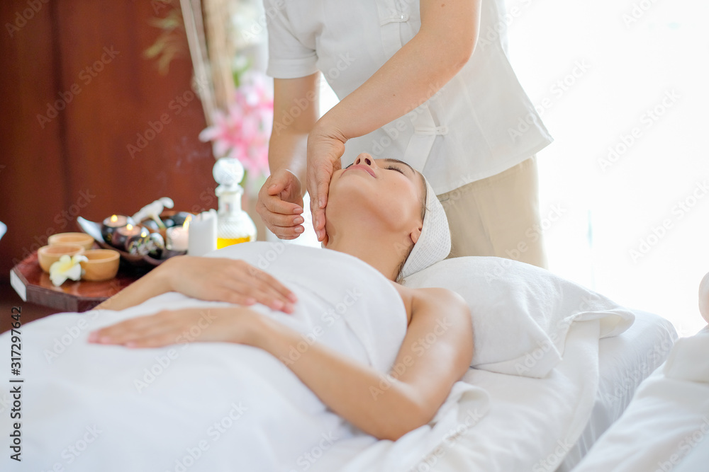 Portrait of Thai masseuse do face massage for young beautiful girl who lie and look up on bed in spa room with day light. Portrait of Thai masseuse do face massage for young beautiful girl who lie and look up on bed in spa room with day light.