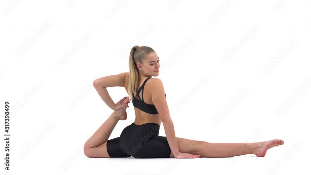 Young fit woman in black sportswear performing stretching exercise being in longitudinal twine position. Sport concept Young fit woman in black sportswear performing stretching exercise being in longitudinal twine position. Sport concept