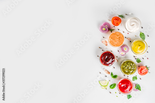 Set of sauces in small bowls - ketchup, mayonnaise, mustard, bbq sauce, pesto, classic burger sauce, with spices and herbs in. White background copy space top view photo