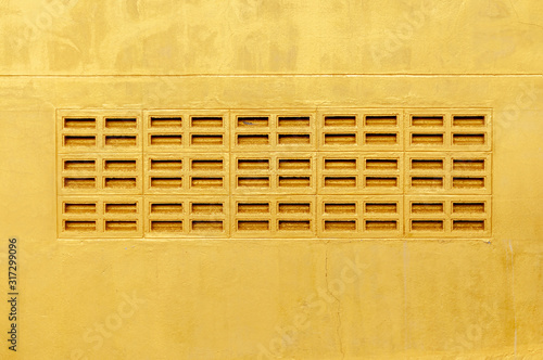 Grunge golden wall background with air flow holes in middle