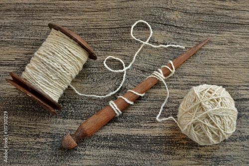 Balls of wool yarn, spool of thread and spindle on wooden background top view close-up.