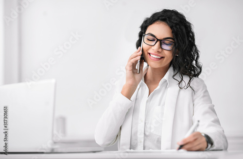 Latin businesswoman talking on phone and writing photo