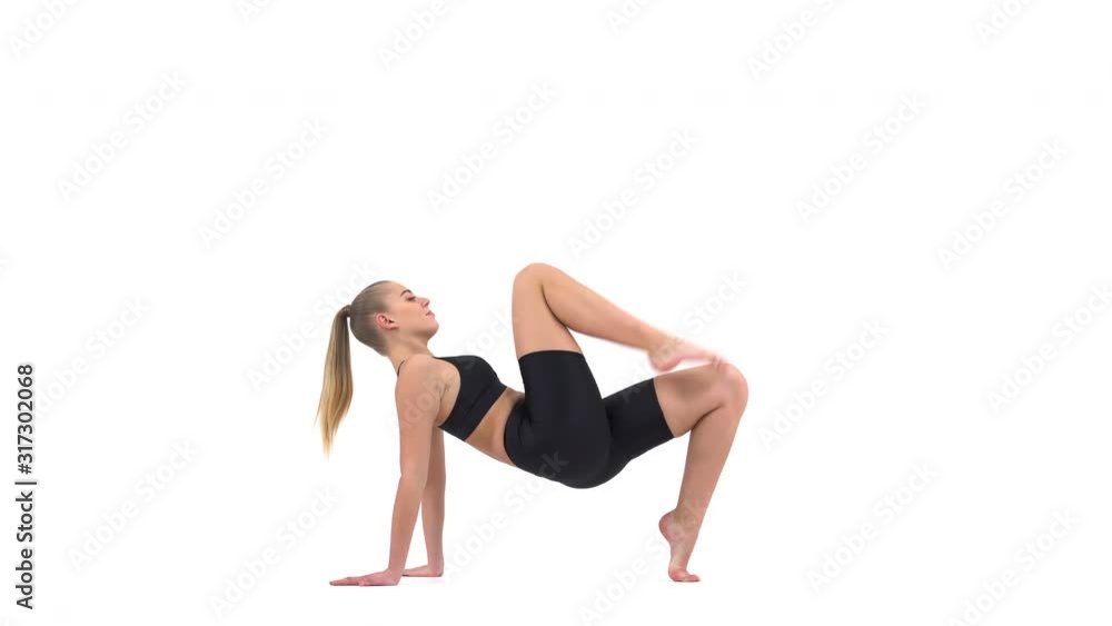 Beautiful Caucasian female gymnast in black sportswear with hair tight in ponytail doing complex stretching exercises. Professional sport concept Beautiful Caucasian female gymnast in black sportswear with hair tight in ponytail doing complex stretching exercises. Professional sport concept