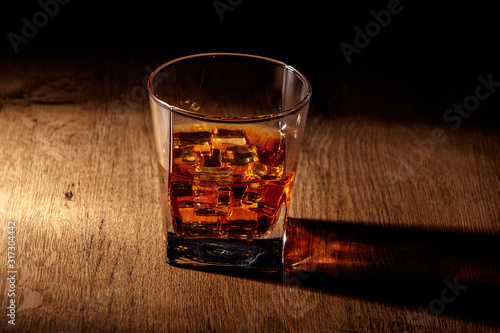 Whiskey with ice or brandy in a glass on a rustic background. Whiskey with ice in a glass. Whiskey or brandy. Selective focus.