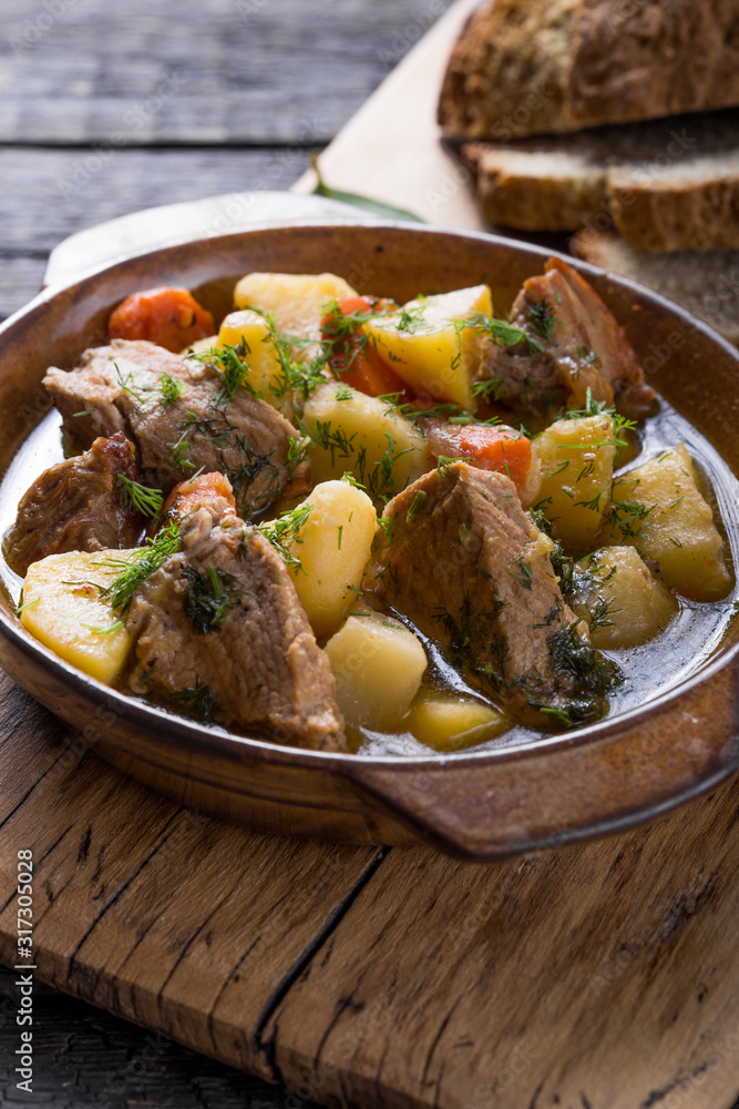 Irish dinner. Beef meat stewed with potatoes, carrots and soda bread on wooden background, top view, copy space. Homemade winter comfort food - slow cooked Irish dinner. Beef meat stewed with potatoes, carrots and soda bread on wooden background, top view, copy space. Homemade winter comfort food - slow cooked