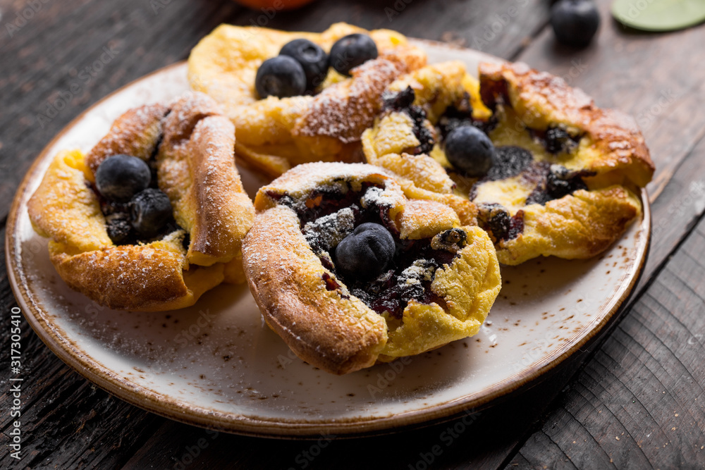 Pannukakku  or Danish pancake with berries topping covered with sugar powder