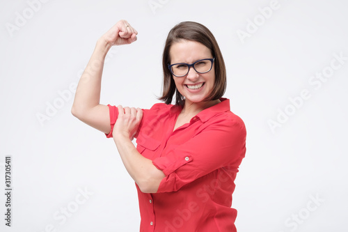 Young caucasian woman flexing her biceps showing her strength and power. Feminism concept. photo