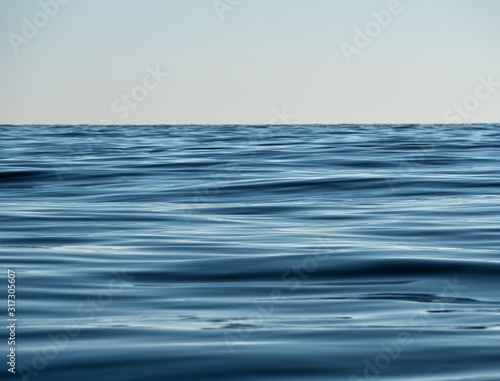 Water texture of deep navy color. Sea, lake or river surface at sky background