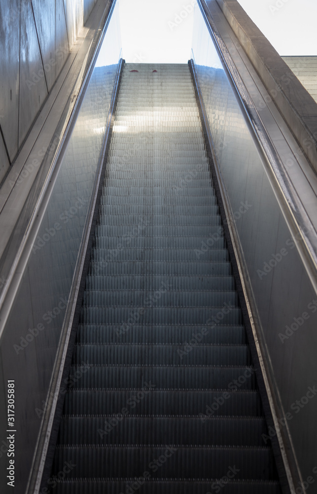 A View of long escalators with stainless steel cladding and exposed concrete walls A View of long escalators with stainless steel cladding and exposed concrete walls