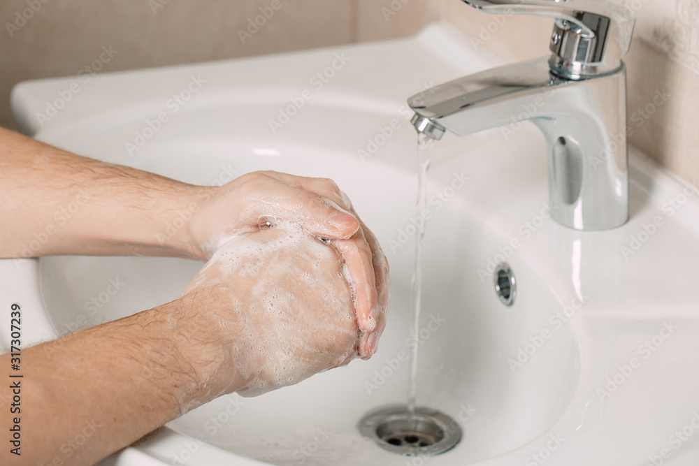 Washing hands under the water tap or faucet without soap. Hygiene concept detail. Beautiful hand and water stream in bathroom.