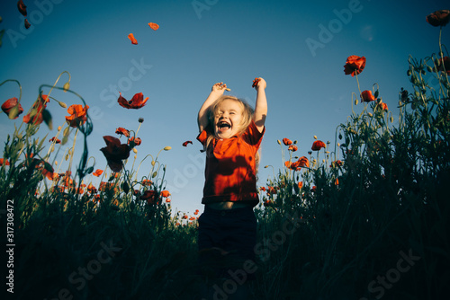 Happiness. Cheerful boy in the field with poppies. Happy walk in nature with a child.