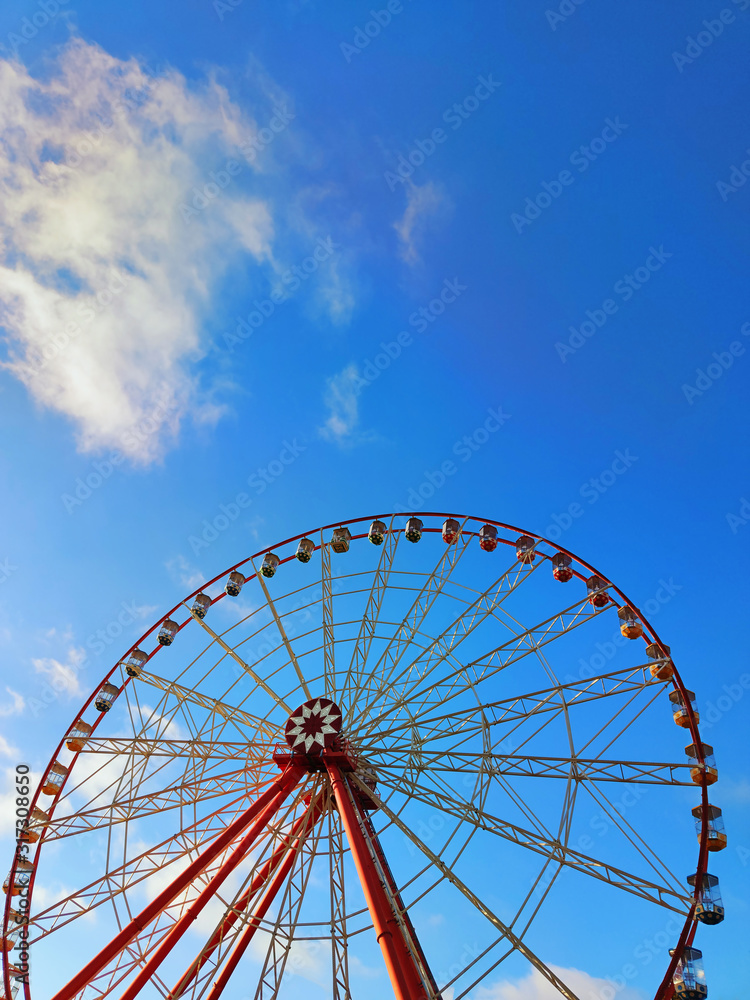 Partly visible ferris wheel with soft clouds
