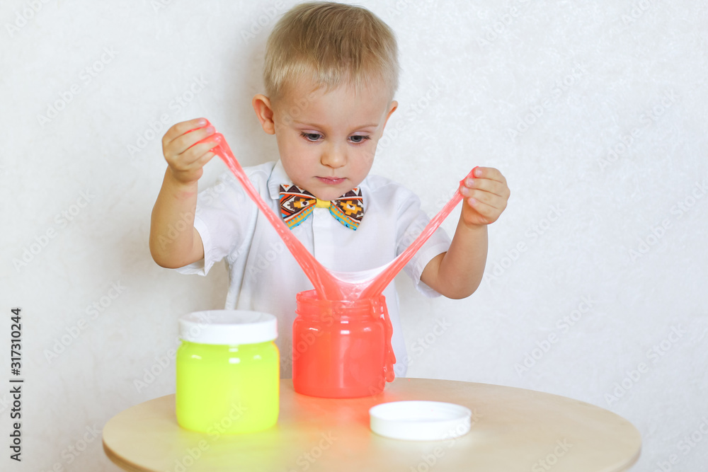 A little toddler boy is intently playing with slime, a sensory play aimed at developing fine motor skills in young children and a fun activity A little toddler boy is intently playing with slime, a sensory play aimed at developing fine motor skills in young children and a fun activity