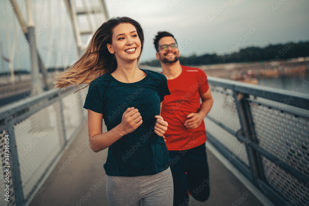 Early morning workout. Happy couple running across the bridge