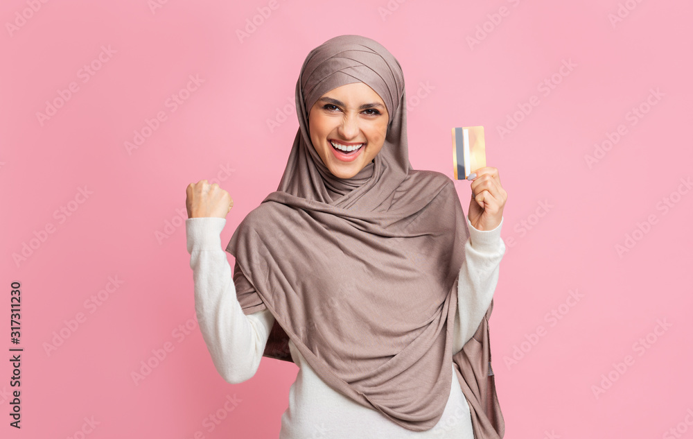 Happy islamic woman in hijab celebrating success with gold credit card Happy islamic woman in hijab celebrating success with gold credit card