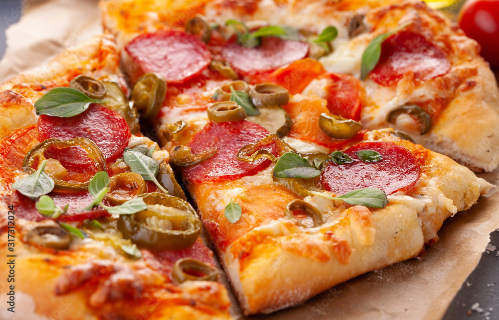 Fototapeta premium Homemade spicy pepperoni pizza and cooking ingredients. Pepperoni pizza on a gray wooden table.