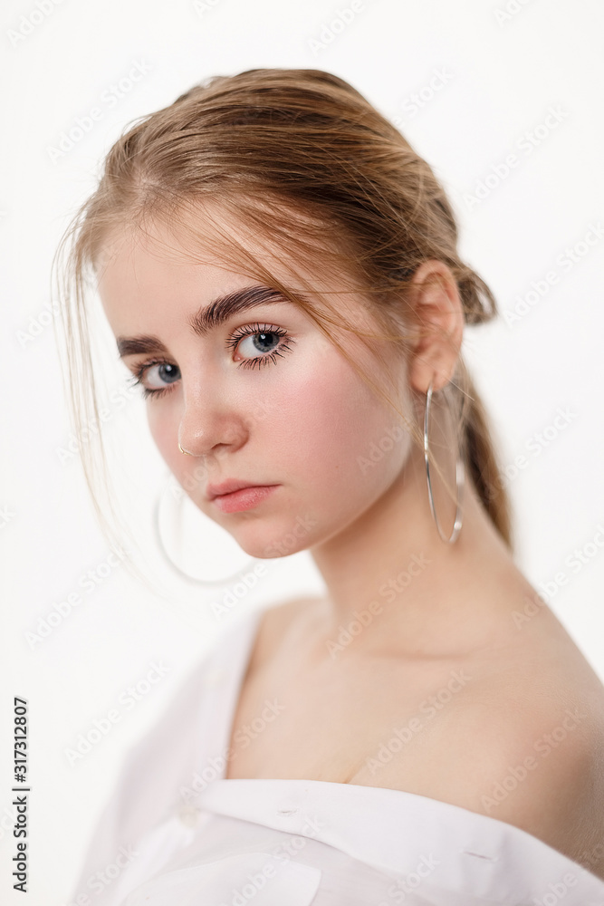 portrait of cute thoughtful teen model wearing shirt posing with bare shoulders. caucasian skinny young female with blond hair isolated on white background. sensual natural pretty girl poses in studio