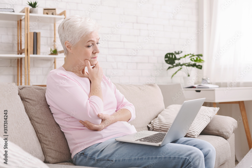 Puzzled senior lady looking at laptop with perplexity Puzzled senior lady looking at laptop with perplexity