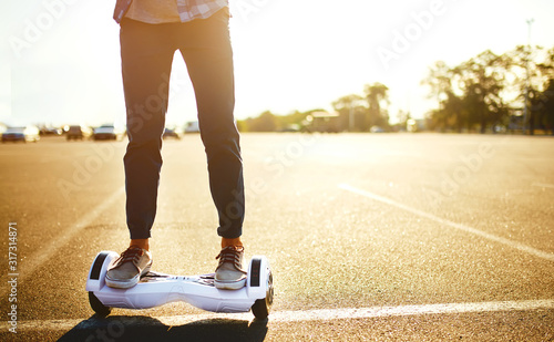 Legs of man riding gyroboard. Person on white hoverboard. Electriic hyroscooter driving. Self-balancing two-wheeled board or hoverboard scooter. photo