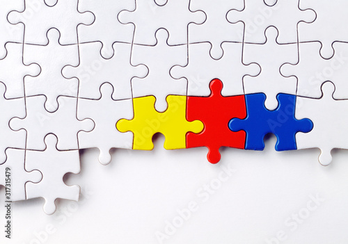ein weißes Puzzle mit drei farbigen Puzzelteilen