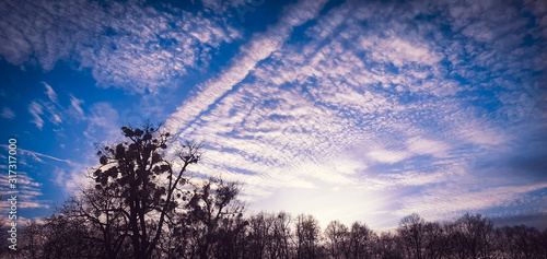 Beautiful altocumulus clouds with sunshine rays and blue sky photo