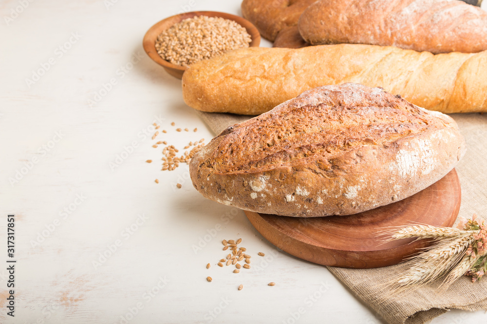 Different kinds of fresh baked bread on a white wooden background. side view, copy space.
