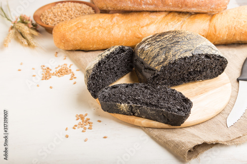 Sliced black bread with different kinds of fresh baked bread on a white wooden background. side view, copy space.