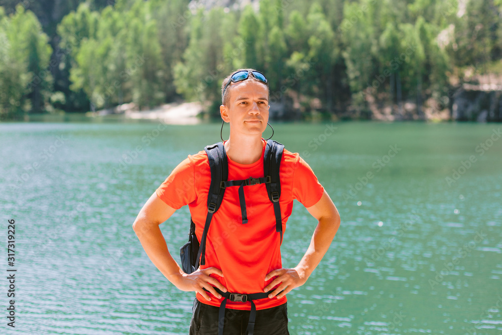 Young man with backpack near big lake. Active healthy lifestyle adventure journey vacations.