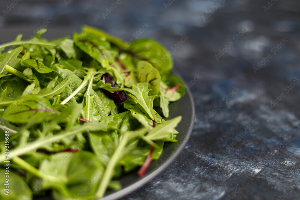 A mixture of green young lettuce, spinach, arugula and young beetroot. Healthy diet. Vegetarian breakfast. On a dark background. A mixture of green young lettuce, spinach, arugula and young beetroot. Healthy diet. Vegetarian breakfast. On a dark background.