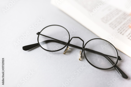 reading glasses and a book on a gray background. low vision reading concept
