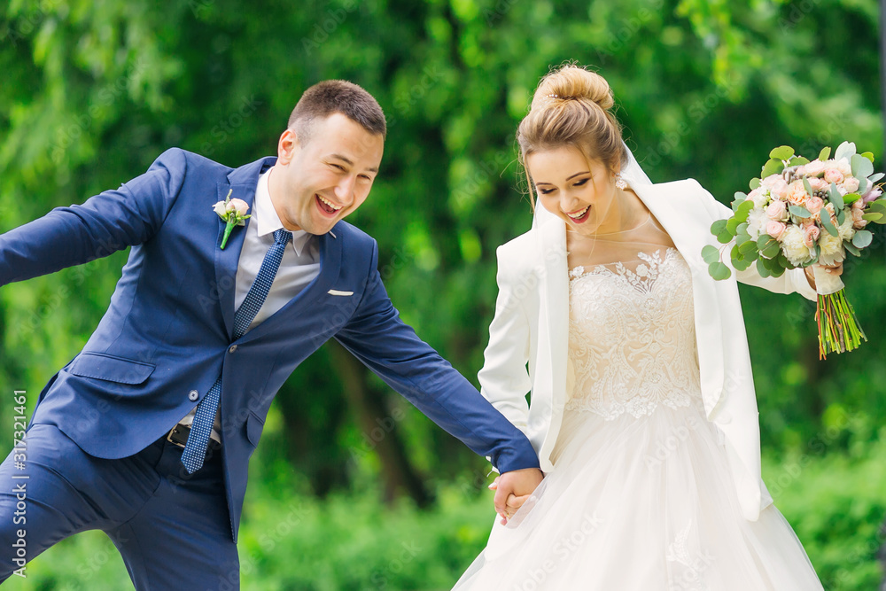 newlyweds hold hands and have fun. bride in dress holds wedding