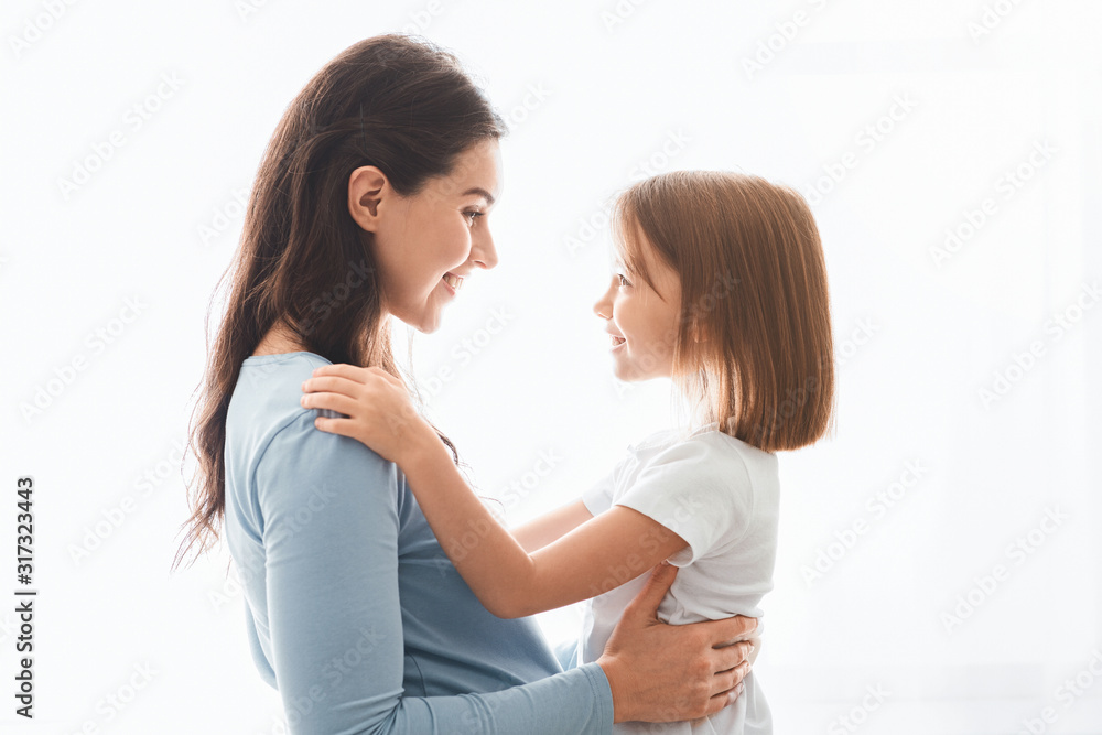 Lovely pregnant mother and daughter cuddling over white background Lovely pregnant mother and daughter cuddling over white background