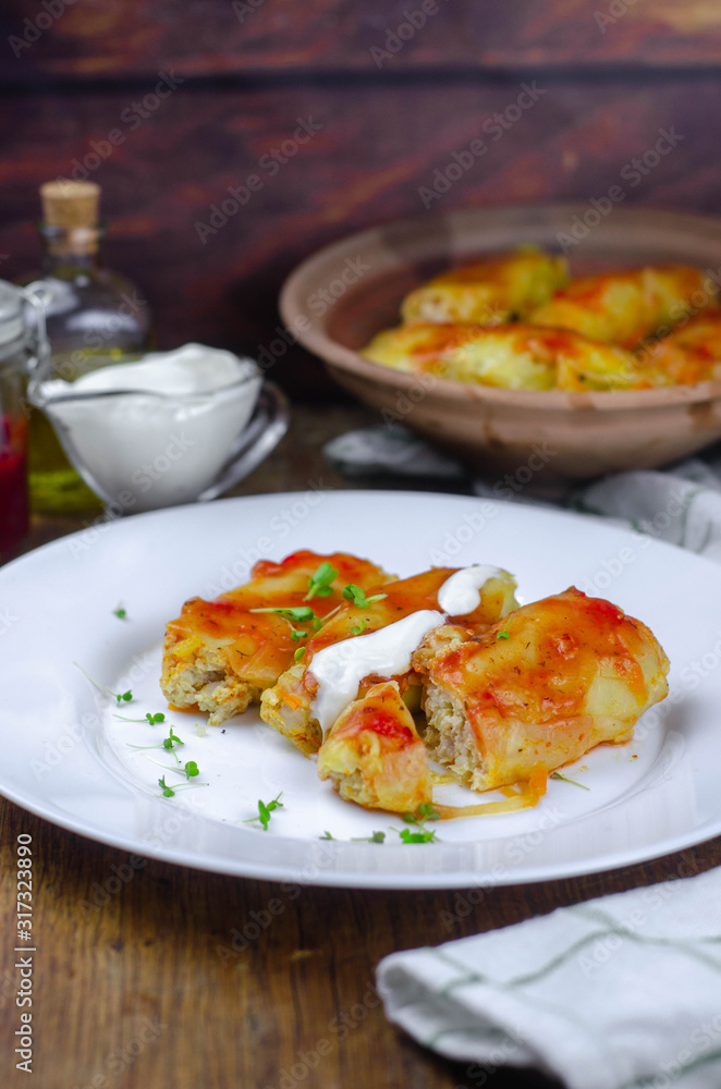 Homemade cabbage rolls with carrots, red tomato sauce and cream on a white plate Homemade cabbage rolls with carrots, red tomato sauce and cream on a white plate