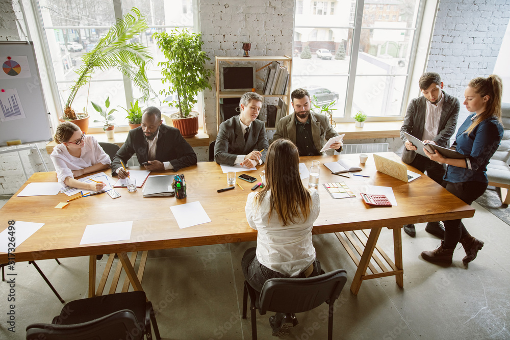 Top view. Group of young business professionals having a meeting. Diverse group of coworkers discuss new decisions, plans, results, strategy. Creativity, workplace, business, finance, teamwork.