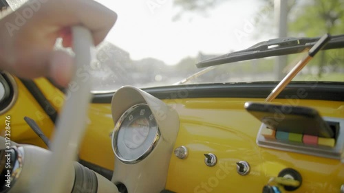 Close Up Of Steering Wheel And Hand Driving Classic Yellow Fiat Car in Europe traveling during the day
