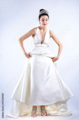 Portrait of irritated angry bride woman in beautiful white wedding dress stand screaming hand-waving dress hem isolated on light background. Wedding celebration concept. Copy space for advertisement